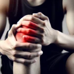 A close-up of a person holding their knee with both hands, showing signs of pain. The knee area is highlighted in red to indicate pain or injury. The